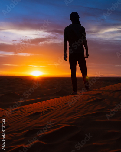 silhouette of person walking in the desert at sunset - Merzouga  Morocco