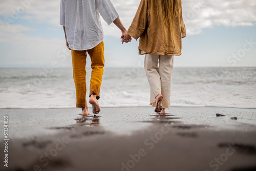 Young loving couple shown from behind holding hands on a beach © Denis