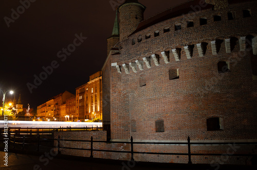 Kraków Barbican by night. Historic fortified gateway of the Old Town of Krakow, Poland. With bus light trails.