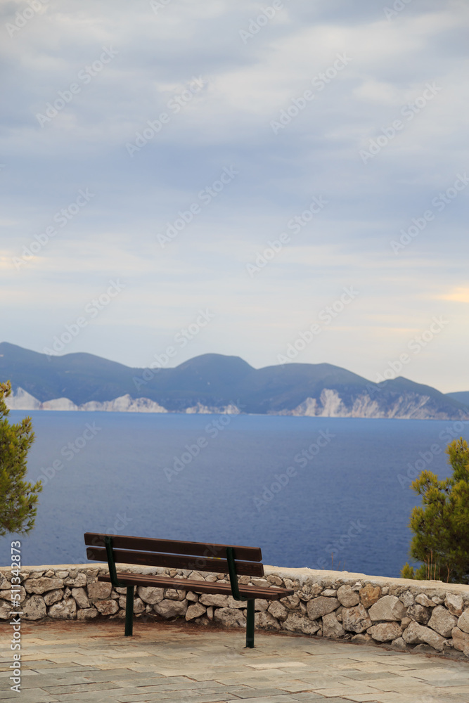 A lonely bench on the hill of Assos peninsula with a fantastic view on Cephalonia island azure sea water and cliffs. Extremely popular travel destination in Greece, Europe.