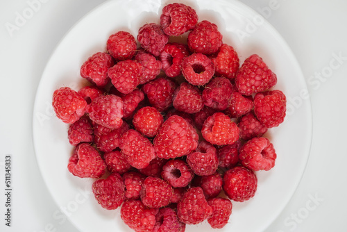 Ripe juicy raspberry on a white plate