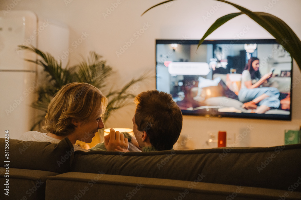 Young gay couple talking and resting on couch while watching tv Young gay couple talking and resting on couch while watching tv