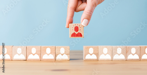 Person icon on wooden cube with hand picked different from the crowd