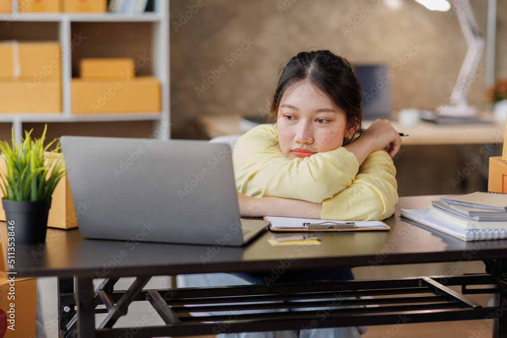 Startup SME small business entrepreneur of freelance Asian woman wearing apron using laptop and box to receive and review orders online to prepare to pack sell to customers, online sme business ideas. Startup SME small business entrepreneur of freelance Asian woman wearing apron using laptop and box to receive and review orders online to prepare to pack sell to customers, online sme business ideas.