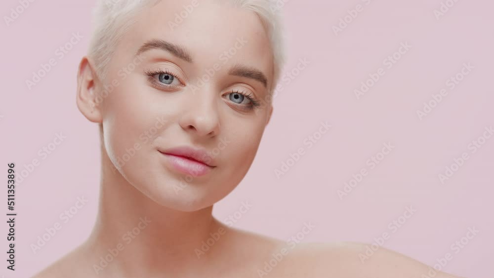 Slim pretty young light-haired Caucasian woman with naked shoulders strokes her face and neck smiling for the camera on pale pink background | Skincare concept Slim pretty young light-haired Caucasian woman with naked shoulders strokes her face and neck smiling for the camera on pale pink background | Skincare concept
