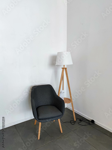 Stylish armchair with a lamp near a white wall. Interior Design