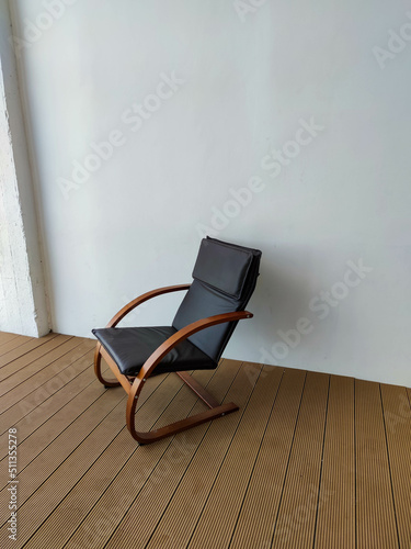 Stylish armchair near white wall, room with parquet floor. Interior Design