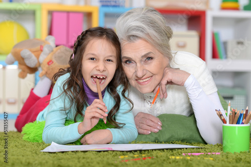 Portrait of cute little girl drawing with grandmother