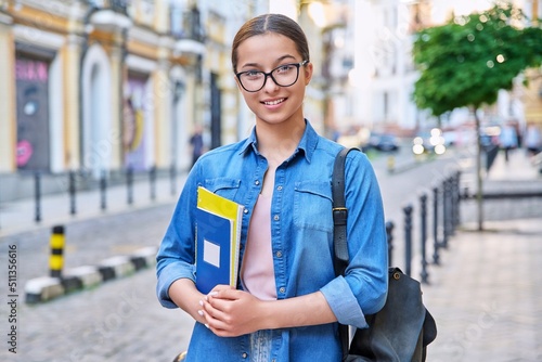 Outdoor portrait of smiling teenage female student looking at camera in city