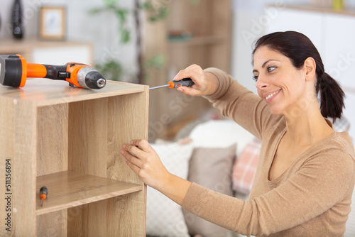 cheerful woman assembles home furniture photo
