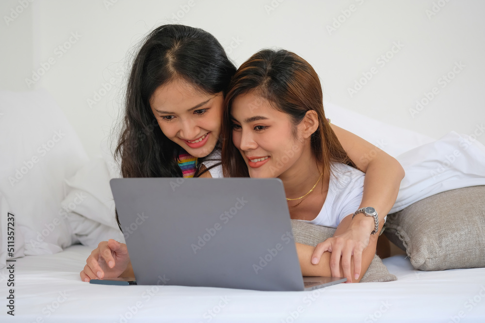 lgbtq lgbt concept homosexuality Two beautiful women happily express their love for each other playing laptop computers in their comfortable homes. lgbtq lgbt concept homosexuality Two beautiful women happily express their love for each other playing laptop computers in their comfortable homes.