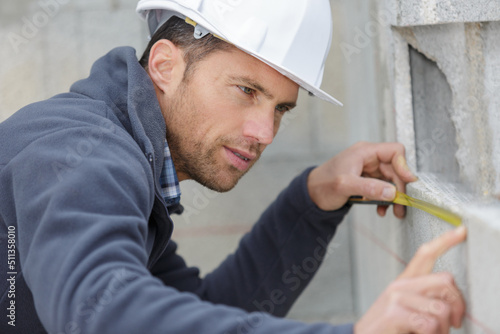 male builder measures on the wall with a rule
