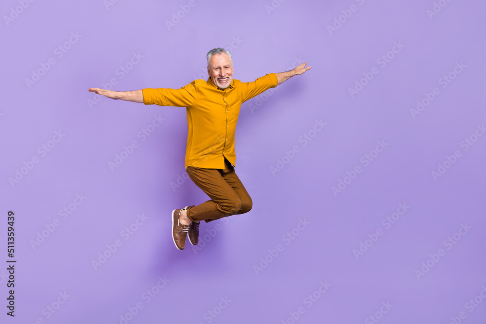 Full body photo of cheerful aged man have fun hands wings airplane isolated over purple color background