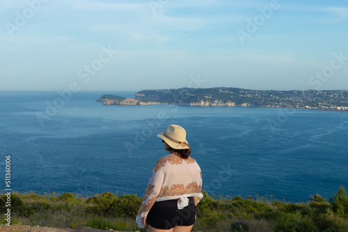 woman with hat contemplating the cove, tourist on the beach