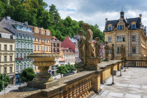 Panoramic view of the streets of Karlovy Vary (Czech Republic) with colorful elegant houses on the mountain surrounded by green foliage. Ancient sculptural group
