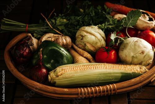 Grocery basket, rustic basket with vegetables: corn, mushrooms, turnips, dill, tomatoes, buryak, pepper, garlic. Assortment of seasonal vegetables for a healthy diet photo