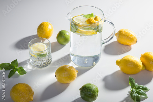 The ingredients for lemonade are on the table: lemons, lime, mint, sugar. A glass and a decanter of a refreshing summer seasonal drink. Making a drink at home.