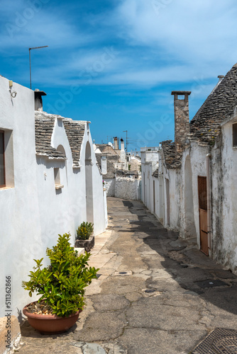 wąska uliczka w Alberobello biegnąca pośród małych zabytkowych budynków zwanych Trullo