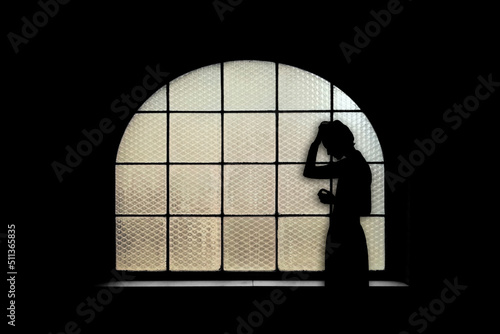 Donna in piedi triste alla finestra in controluce tristezza e disperazione photo