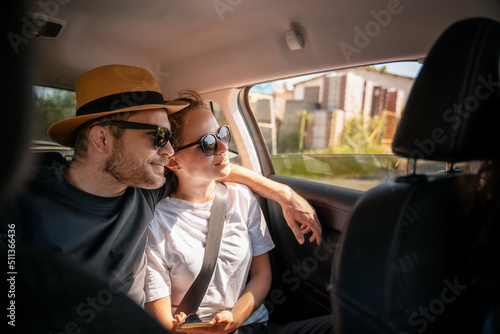 Obraz na płótnie Young cheerful happy couple of travelers sitting in the car in the back seat looking out the window w salonie