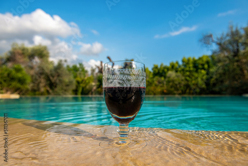 czerwone wino w kieliszku stojącym na skraju basenu