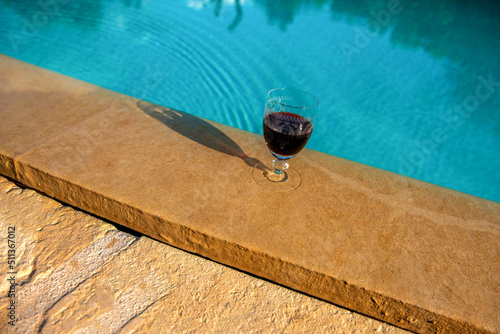 kieliszek z czerwonym winem na skraju basenu