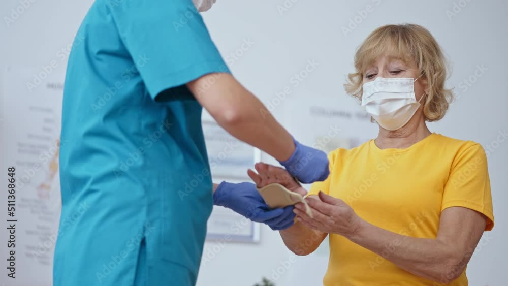 Female doctor removing cast from patient's hand, healed arm, treatment