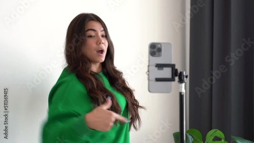 Cheerful teenage girl dancing at camera filming video using phone on tripod at home, creating her trendy content on a mobile app to share on social media and networking service. 4k footage