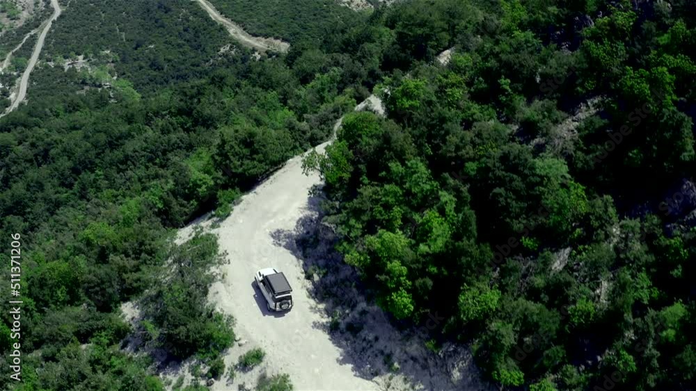 Aerial of Offroad truck driving on a narrow mountain road through the forest Aerial of Offroad truck driving on a narrow mountain road through the forest