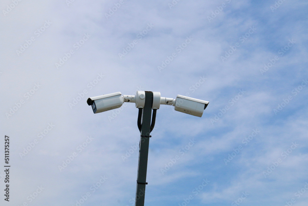 Two CCTV cameras on a pole point in opposite directions. Two CCTV cameras on a pole point in opposite directions.