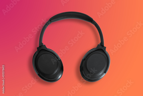 Computer headphones. Black headphones on a orange red background. The concept of listening to music, creating audio, music. Computer work, abstraction and minimalist style.