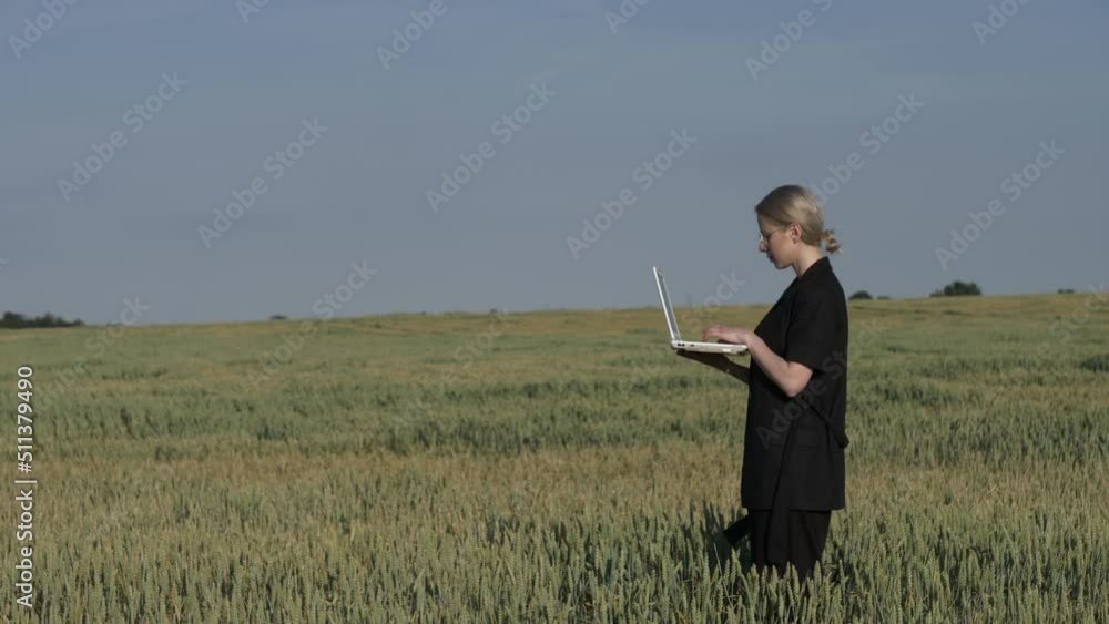 employee of an agricultural firm with a laptop checks the quality of wheat in the field employee of an agricultural firm with a laptop checks the quality of wheat in the field
