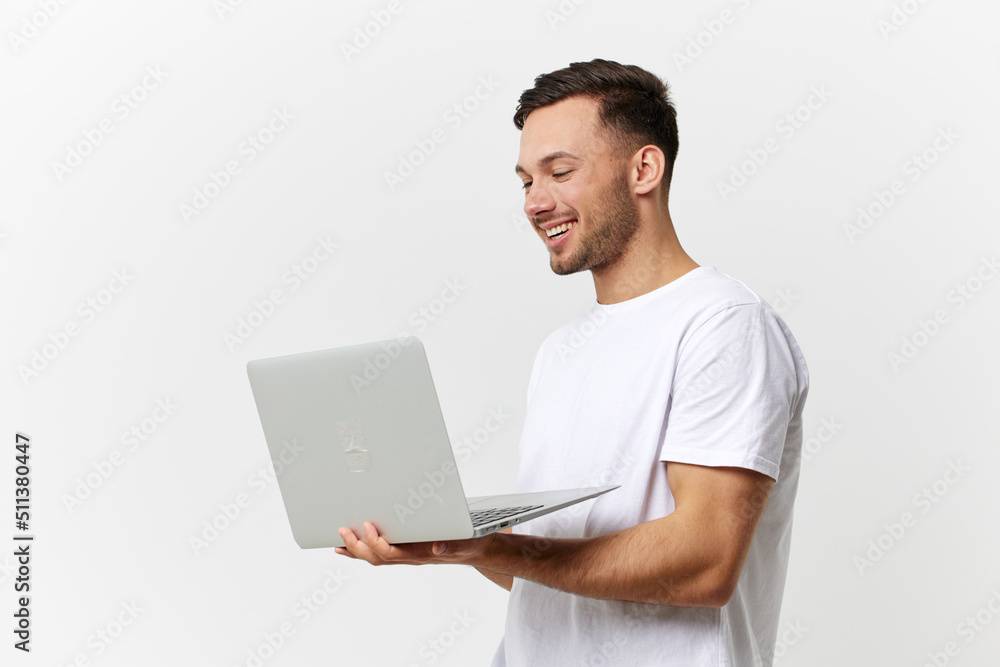 Happy passionate enjoyed tanned handsome man in basic t-shirt chatting with friends by laptop posing isolated on over white studio background. Copy space Banner Mockup. Gadgets lifestyle concept Happy passionate enjoyed tanned handsome man in basic t-shirt chatting with friends by laptop posing isolated on over white studio background. Copy space Banner Mockup. Gadgets lifestyle concept