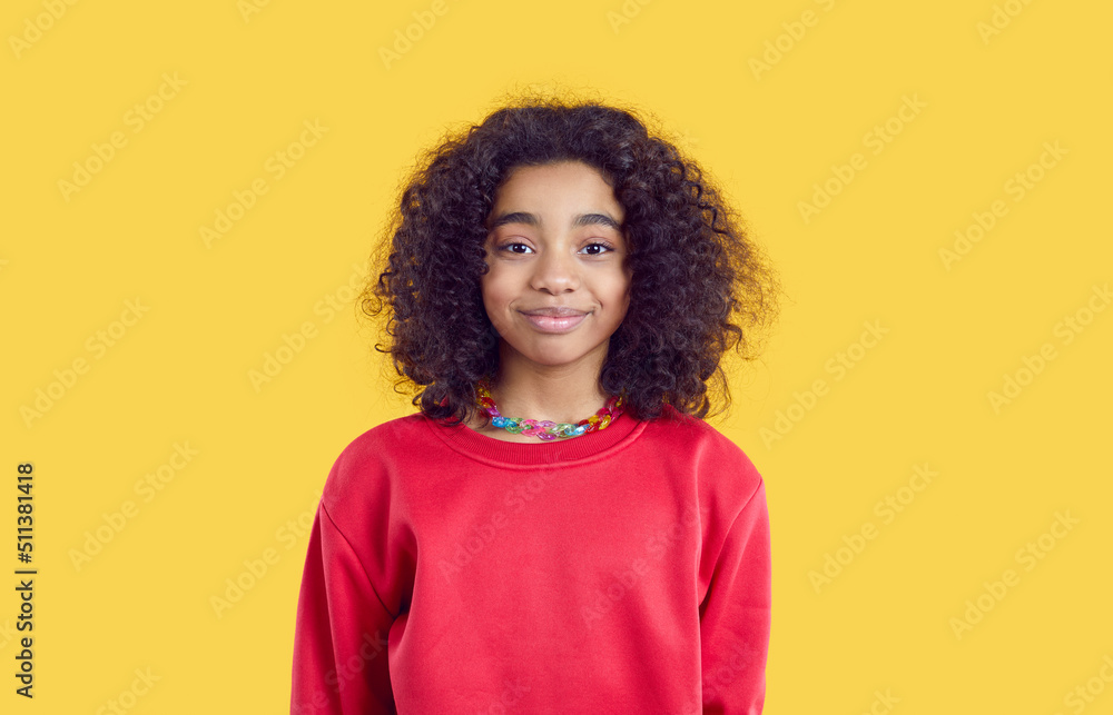 Happy child in casual clothes. Positive little kid isolated on solid bright yellow color background. Studio head shot of pretty African American girl in red sweatshirt looking at camera and smiling Happy child in casual clothes. Positive little kid isolated on solid bright yellow color background. Studio head shot of pretty African American girl in red sweatshirt looking at camera and smiling