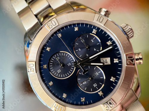 Luxury stainless steel watch with chronograph, dark blue dial and metal bracelet close-up. Macrophotography of watch details