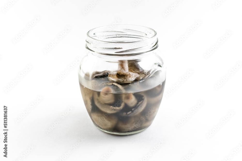 Isolated glass jar with marinated champignon mushrooms on a white background, open snack, home canning Isolated glass jar with marinated champignon mushrooms on a white background, open snack, home canning