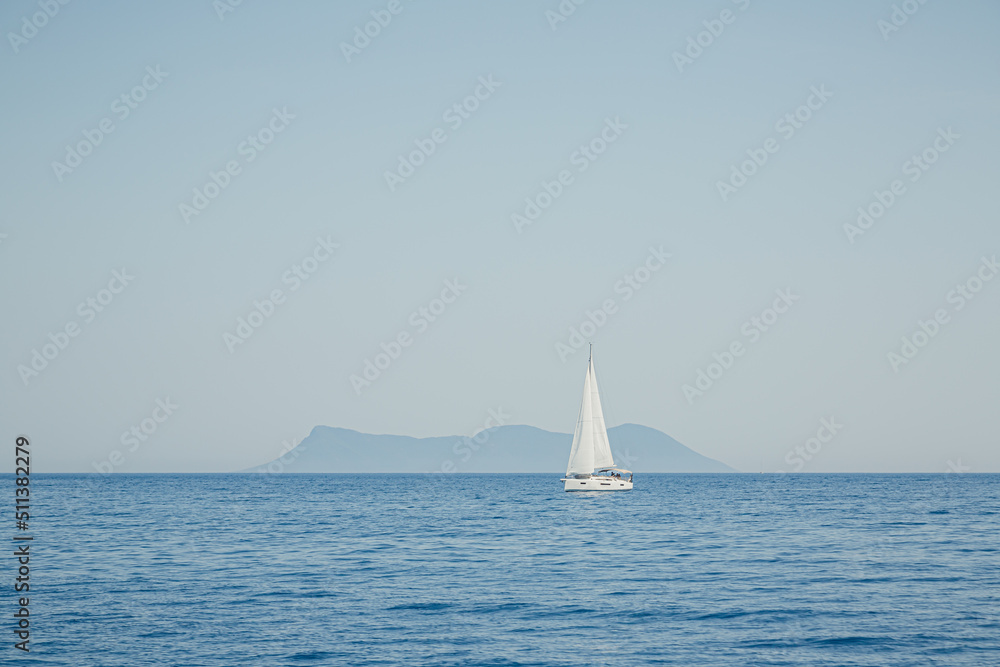 single sailboat on the sea in front of an island