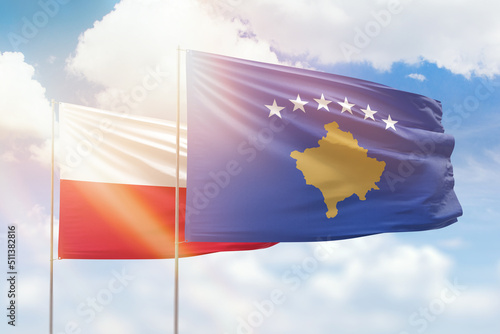 Sunny blue sky and flags of kosovo and poland