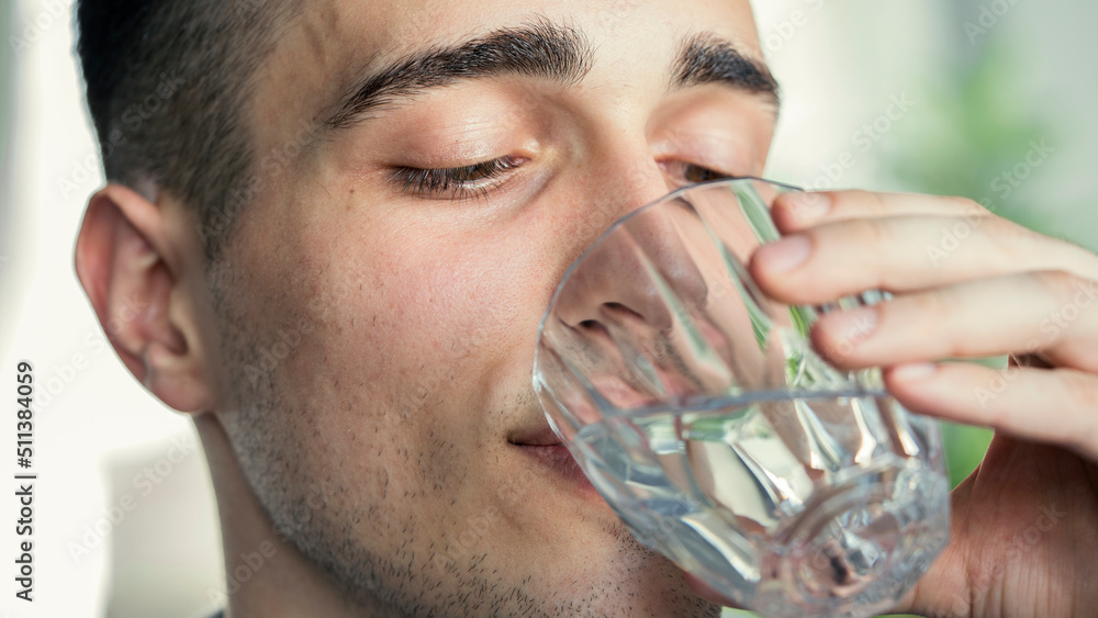 Young man drinks a glass of water Young man drinks a glass of water