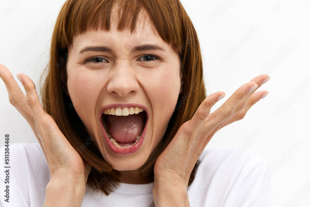 a close horizontal studio photograph of an alarmed, frightened woman with red hair, screaming loudly clutching her head from shock. a close horizontal studio photograph of an alarmed, frightened woman with red hair, screaming loudly clutching her head from shock.