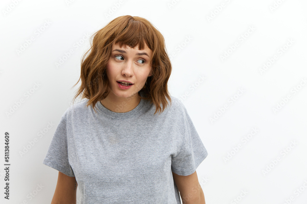a happy, joyful woman in a gray cotton T-shirt stands against a light background, smiling happily and looking away. Horizontal photo with an empty space for inserting an advertising layout a happy, joyful woman in a gray cotton T-shirt stands against a light background, smiling happily and looking away. Horizontal photo with an empty space for inserting an advertising layout