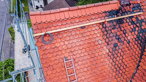 Old house roof with plain tile during repair of broken ridge tile by a roofer