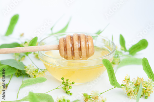 Natural linden honey with linden flowers on a white background