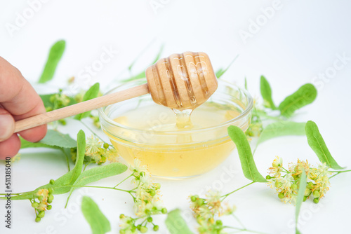 Natural linden honey with linden flowers on a white background