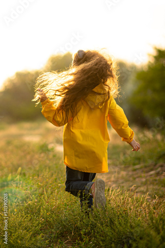 A cute girl of 5 years in a yellow park plays and has a fun with soap bubbles at sunset. Childhood. Sunlight. Rest with the family in nature.