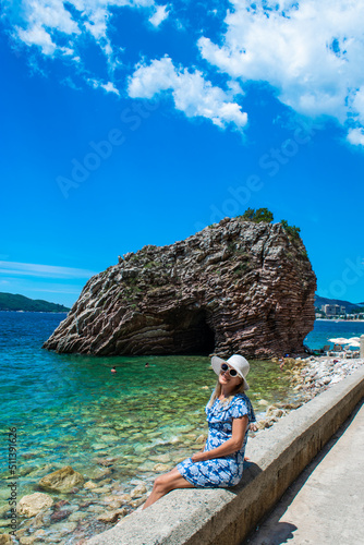 Young woman in front of beautiful rocks on pebble public stone beach. Rafailovici esort towns. Mountenegro. photo