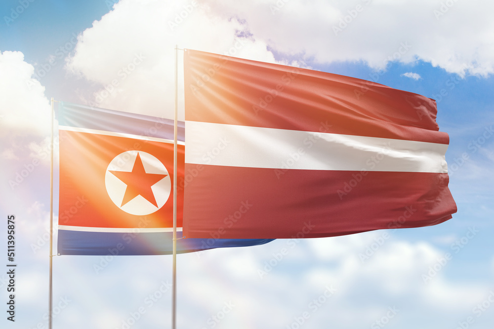 Sunny blue sky and flags of latvia and north korea Sunny blue sky and flags of latvia and north korea