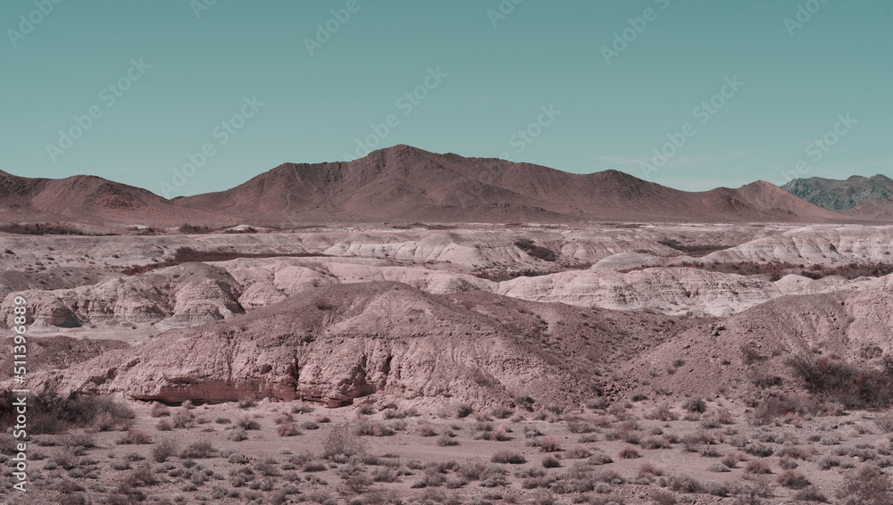 Pastel colors image of a Mojave Desert landscape including badlands and a mountain rage shown near Tecopa in California. Tecopa is located south of Death Valley.