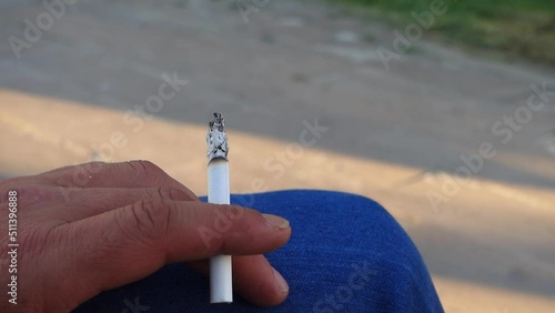 cigarette standing in a person's hand,close-up of a hand holding a cigarette,