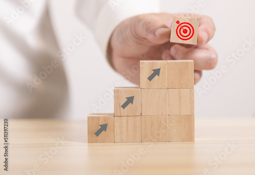 Close up hand stack Wooden block to upside bar graph to stack. Concept for growth graph and route to target.